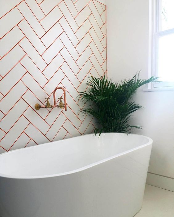 White Subway Tile With Orange Grout in Herringbone Pattern
