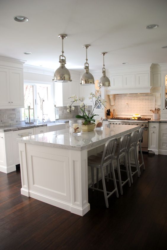 White Kitchen Island With Paneled Base and Metal Stools