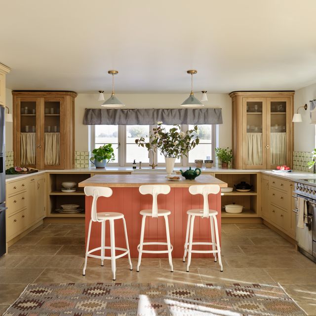 Coral Kitchen Island With White Stools Creates a Cheerful Hub