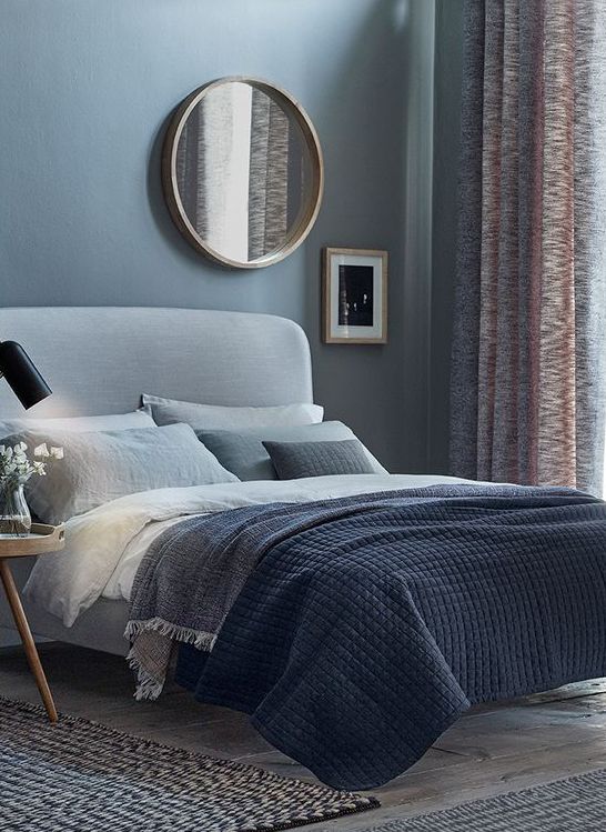 Round Mirror with Wood Frame Softens the Wall Above the Bed