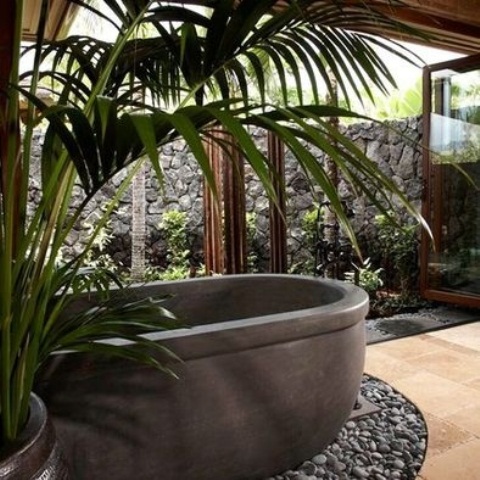 Dark Stone Tub Surrounded by Pebbles Creates a Natural Oasis