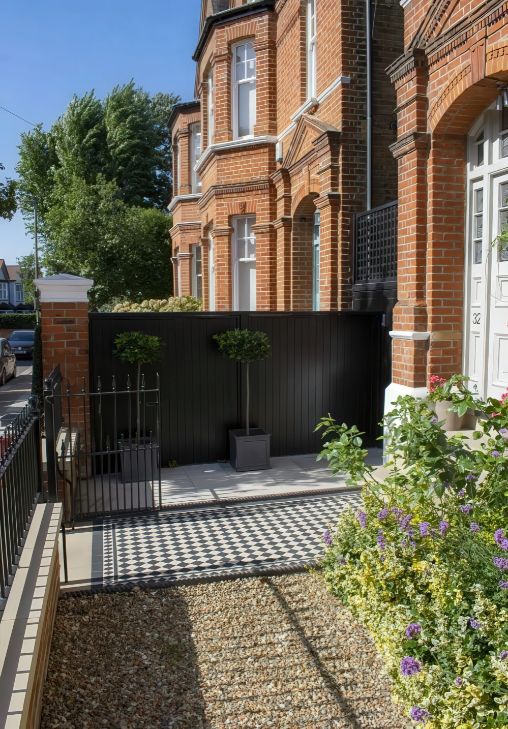 Square Planters With Topiary Trees Add Symmetry to a Dark Fence