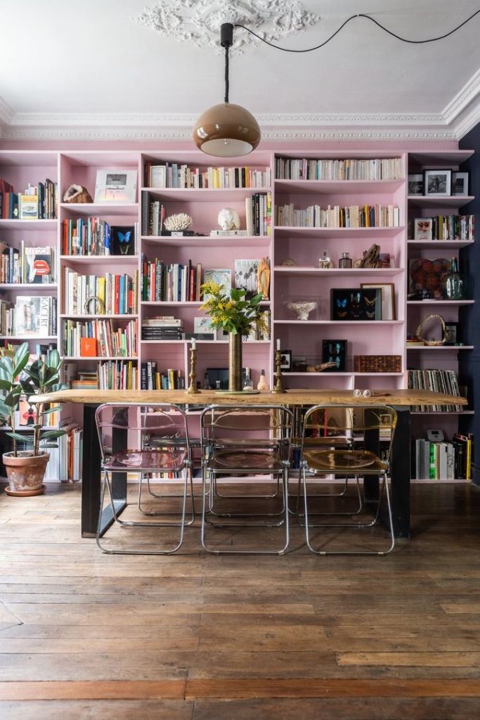 Pale Pink Bookshelves Frame a Dining Area with Clear Chairs